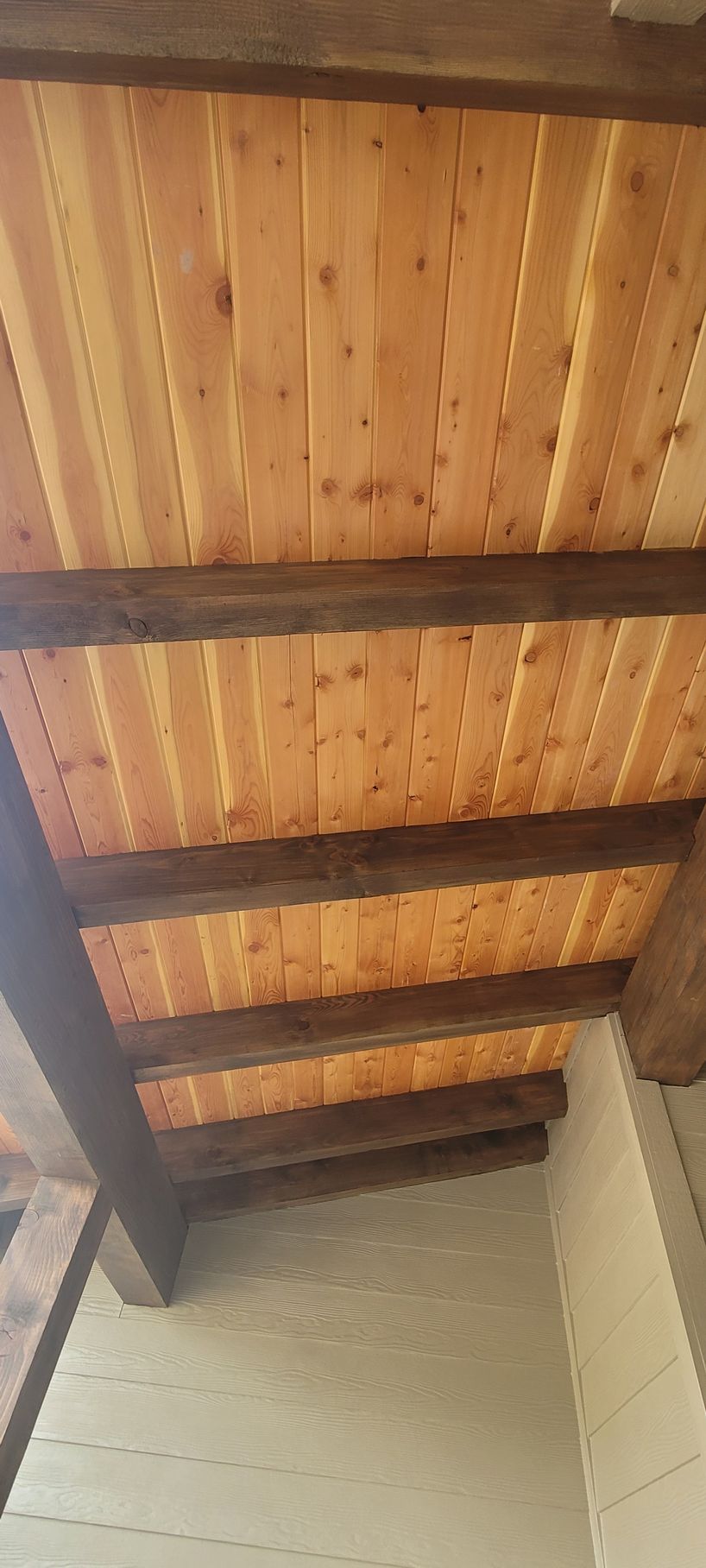 Wooden ceiling with exposed dark beams above white walls in a narrow interior space