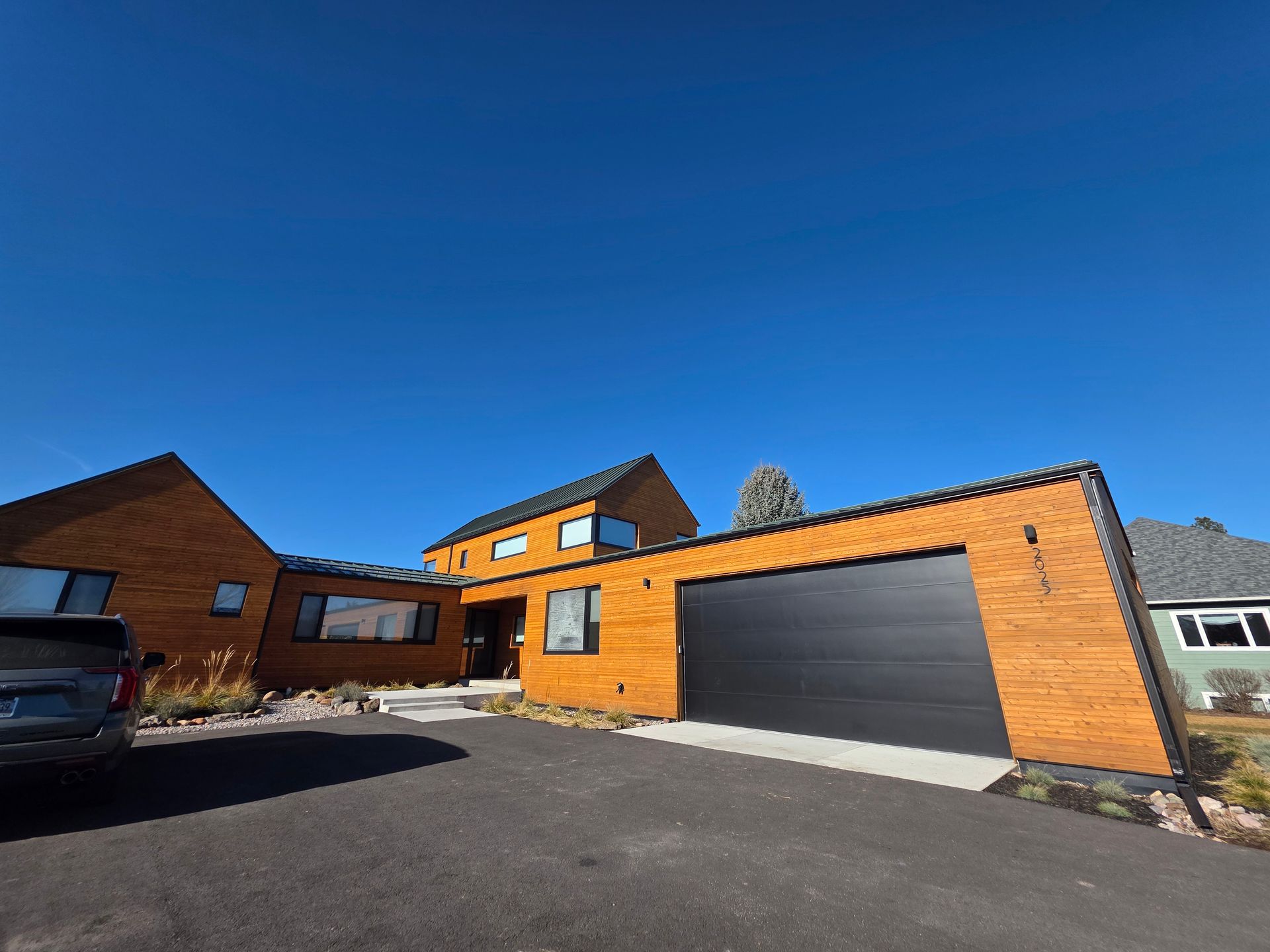 Modern suburban house exterior with orange brick, large gray garage door, and blue sky