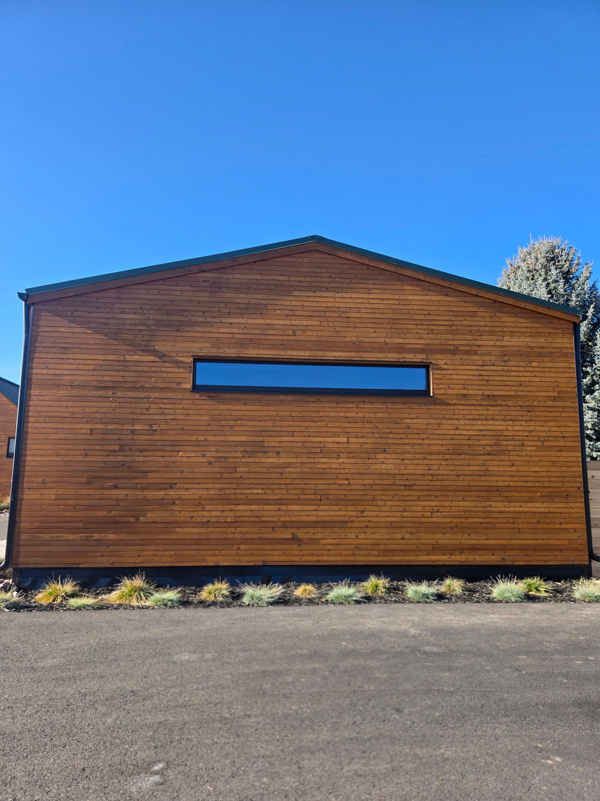 Wooden building with a narrow horizontal window, set against a clear blue sky.