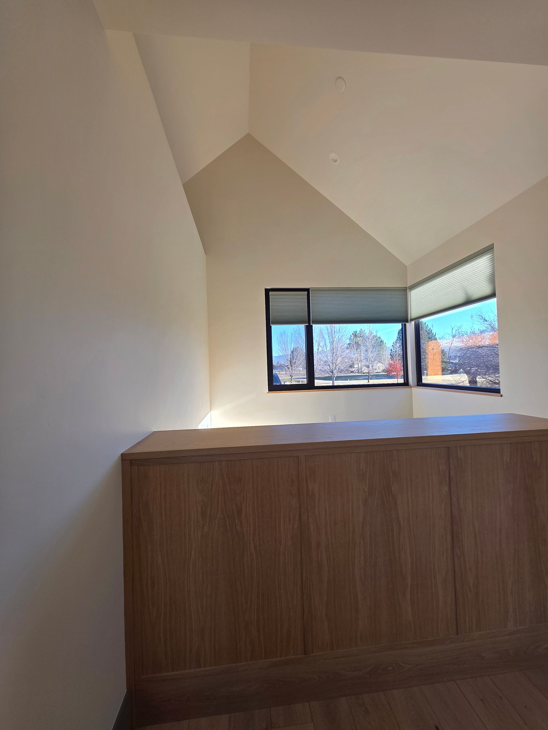 Small room with a wooden cabinet and a bright corner window showing trees outside.