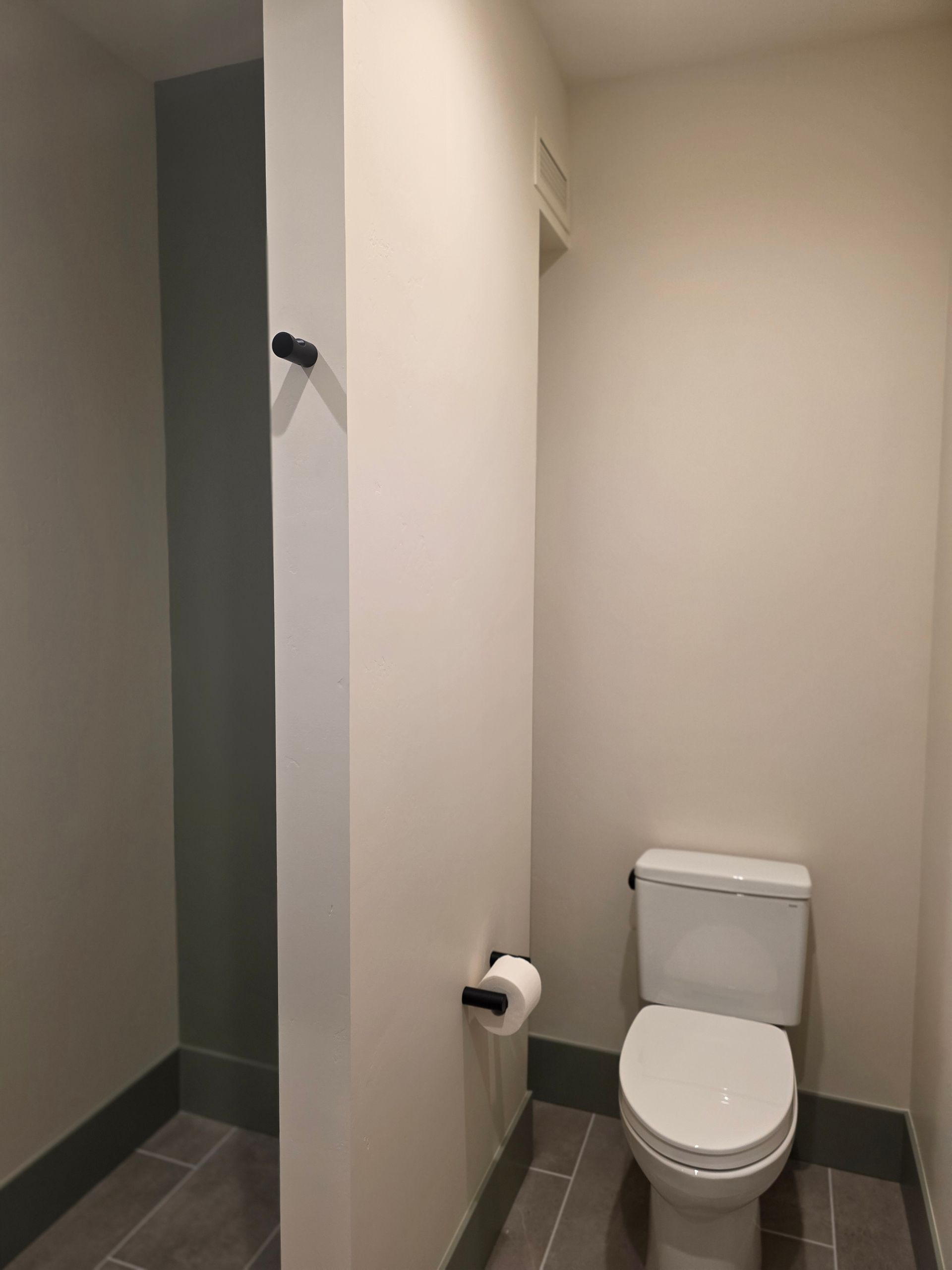 Small bathroom with a white toilet and beige walls, viewed from the doorway.