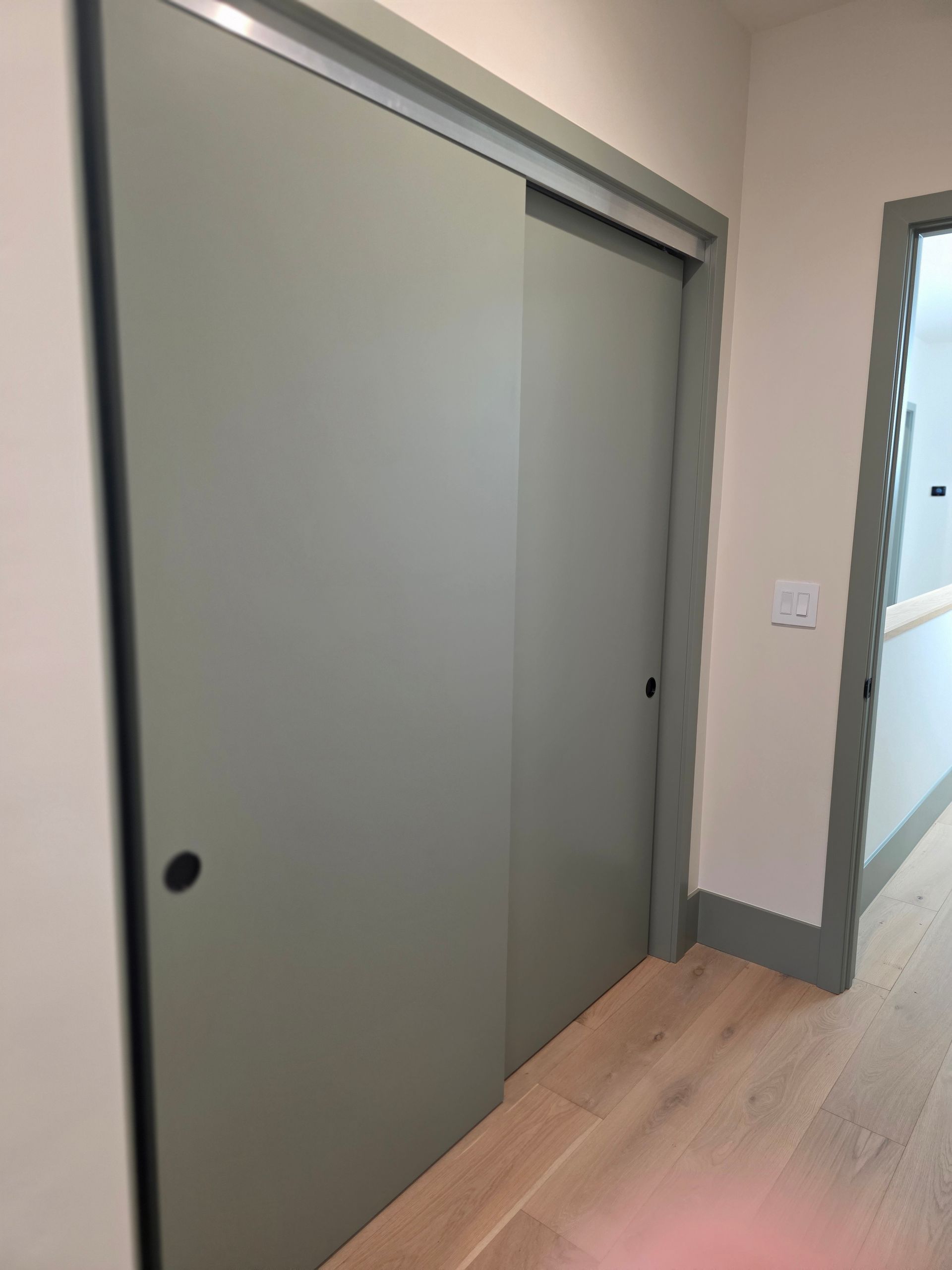 Gray sliding closet door in a modern hallway with light wood floor and beige walls