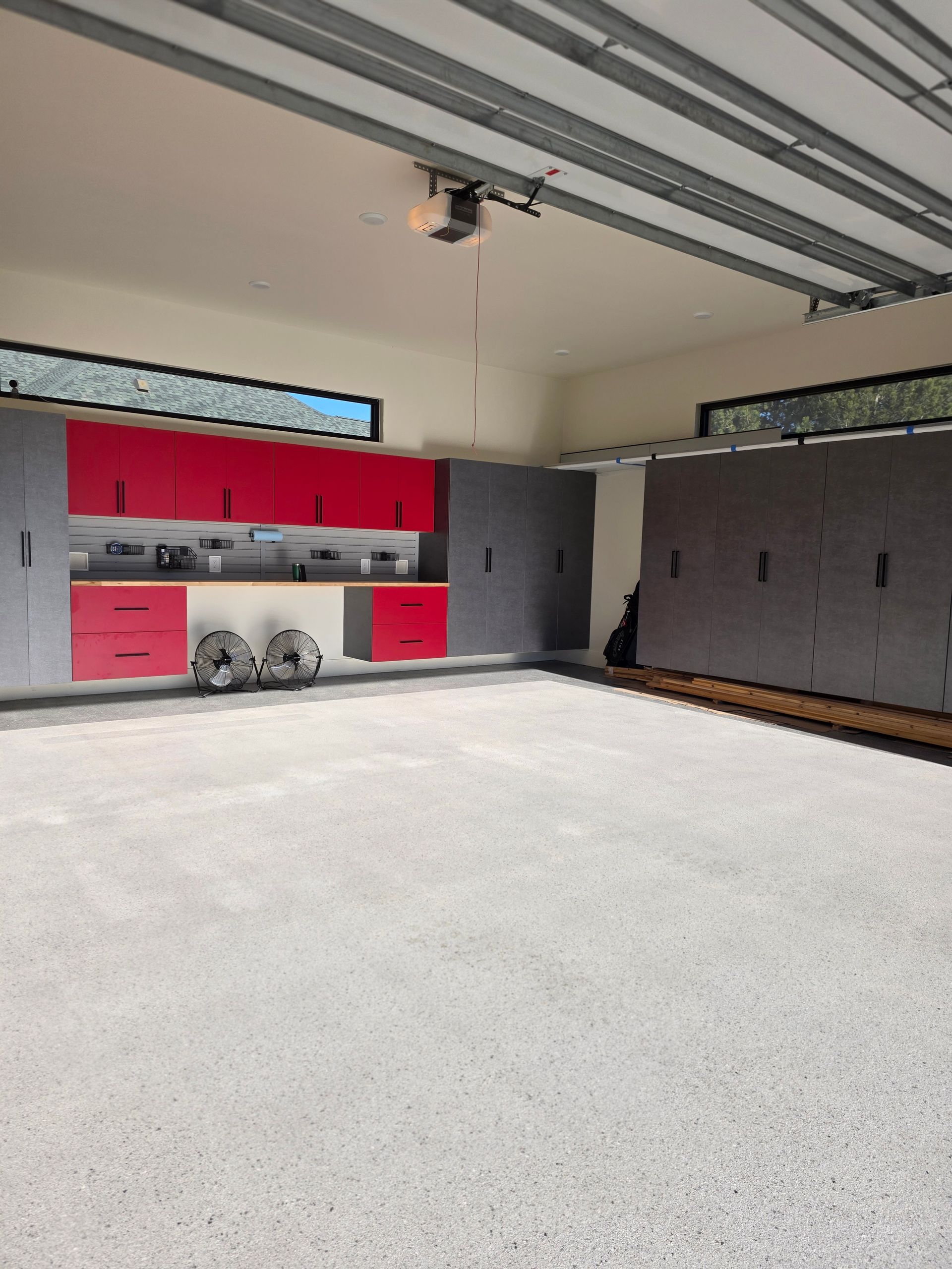 Garage with open cabinets, red and gray storage, and a clean concrete floor.