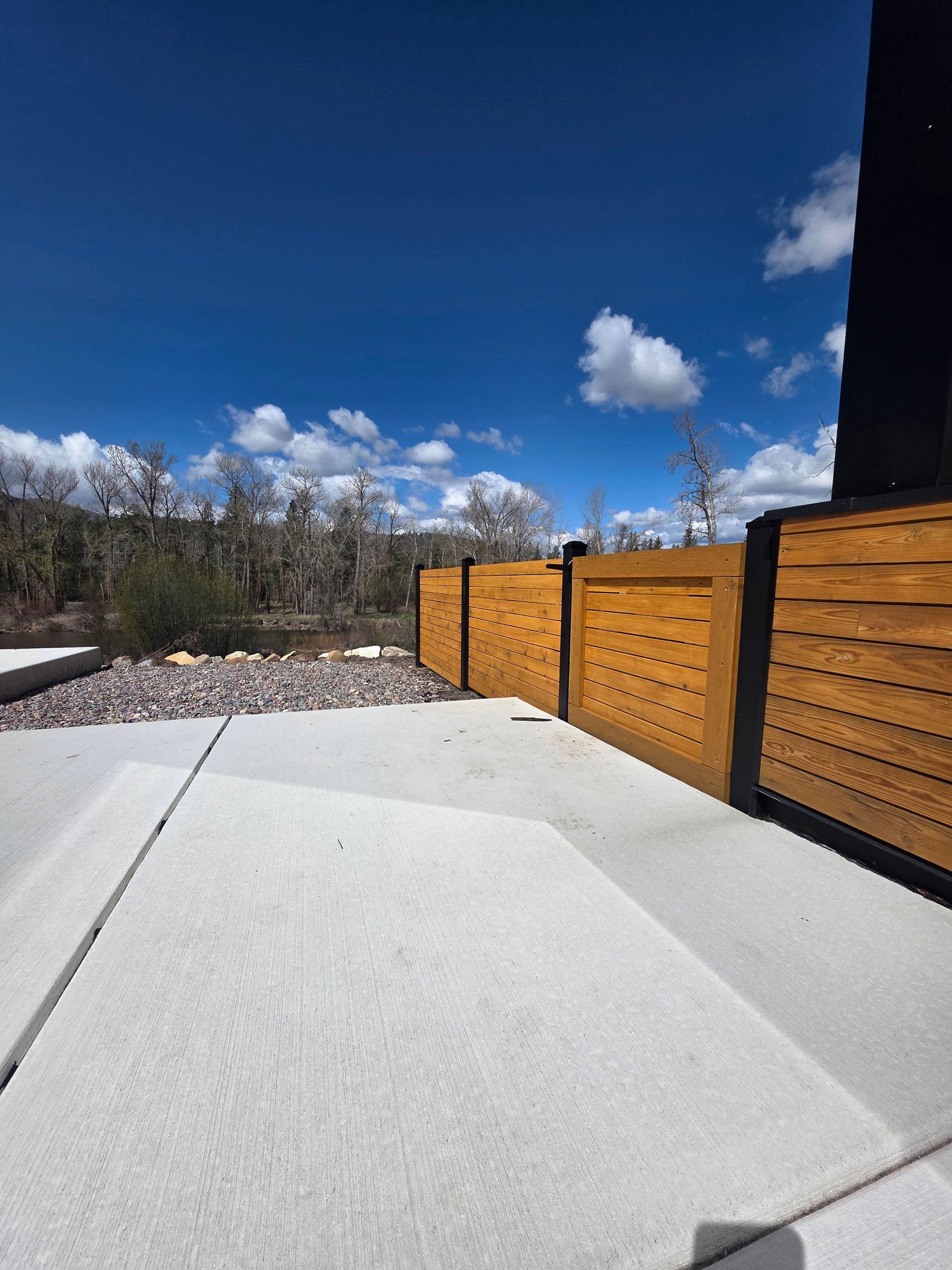 White patio with orange wood fence under a bright blue sky with clouds