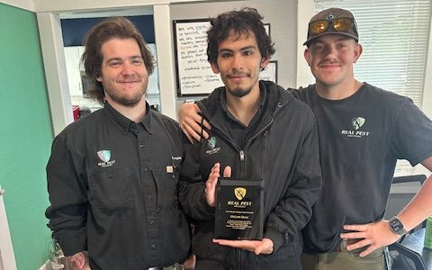 3 men celebrating an anniversary of employment. One is holding a plaque.