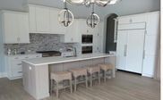 A kitchen with white cabinets and a large island with stools.