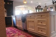 A kitchen with white cabinets and drawers and a pink rug.