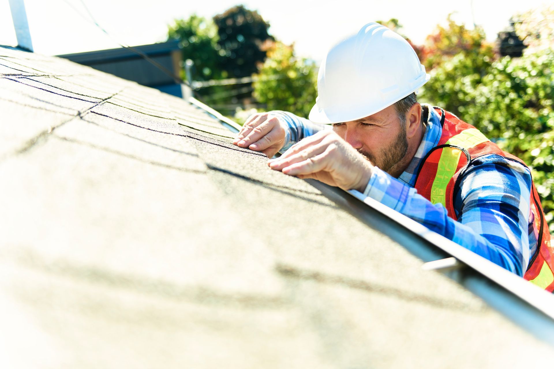Worker in hard hat inspecting a roof under bright sunlight