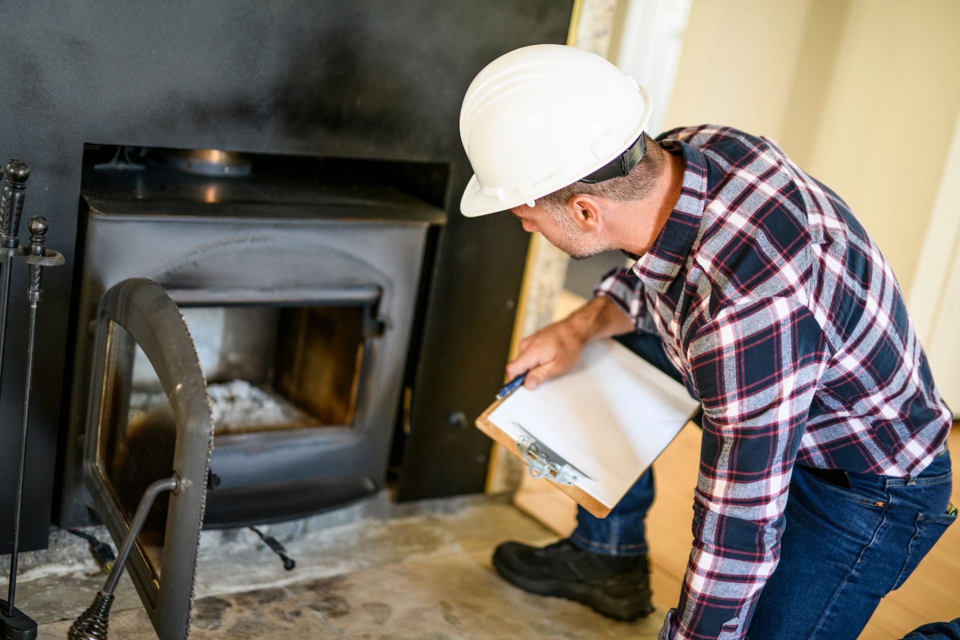 Worker in a hard hat inspecting a fireplace with a flashlight