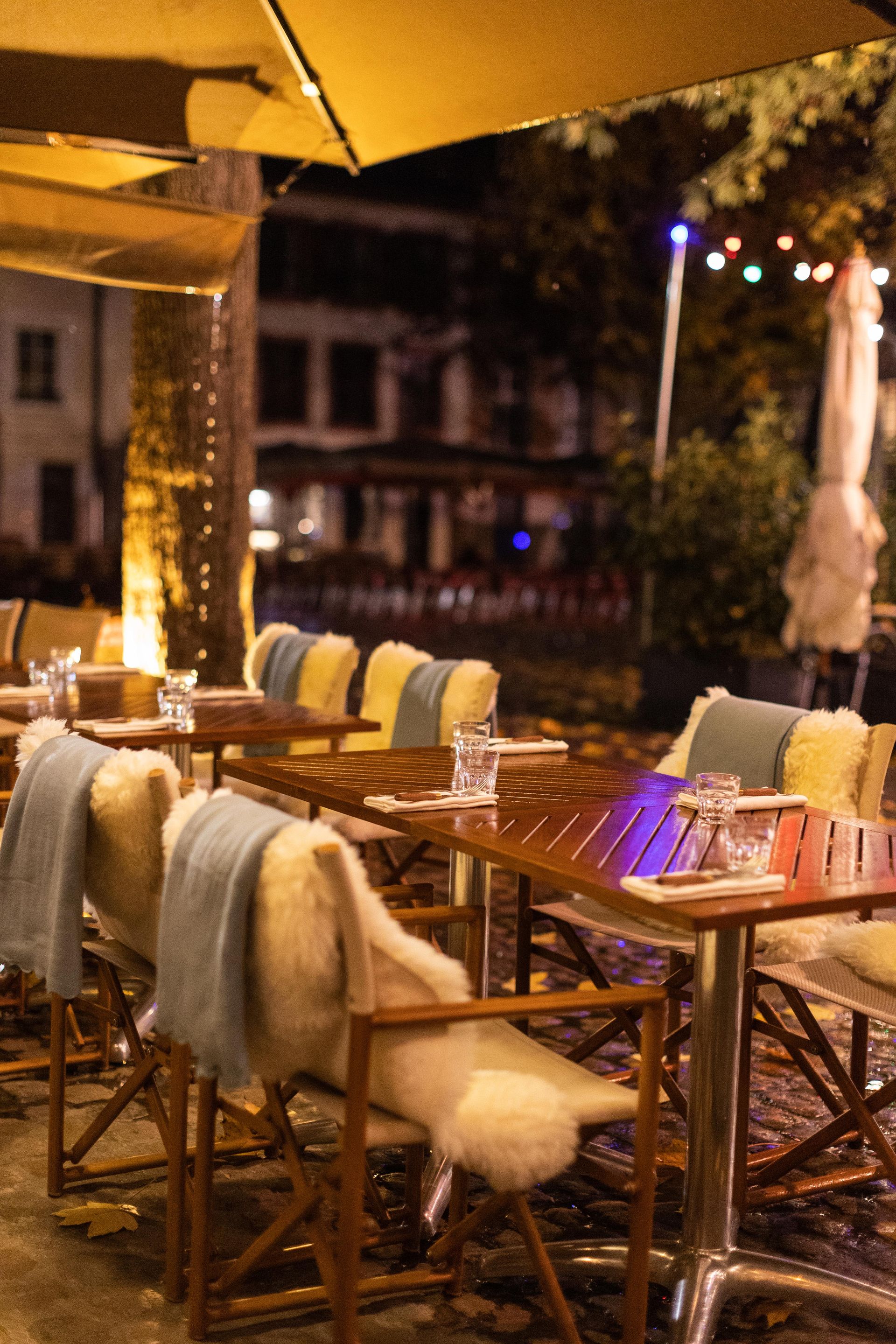 Une rangée de tables et de chaises à l'extérieur d'un restaurant la nuit.