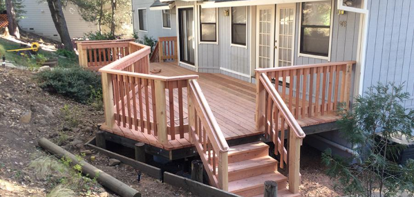 Finished wooden deck with railings and steps wraps around a home after Deck Building Services in Buckeye, AZ completion.