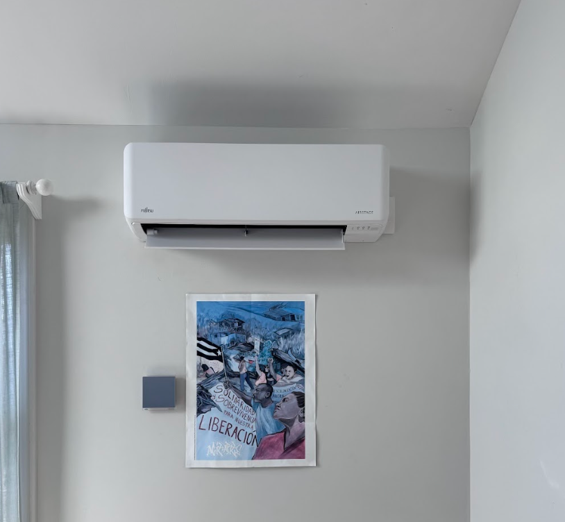 A room with a picture on the wall and a wall mounted air conditioner.
