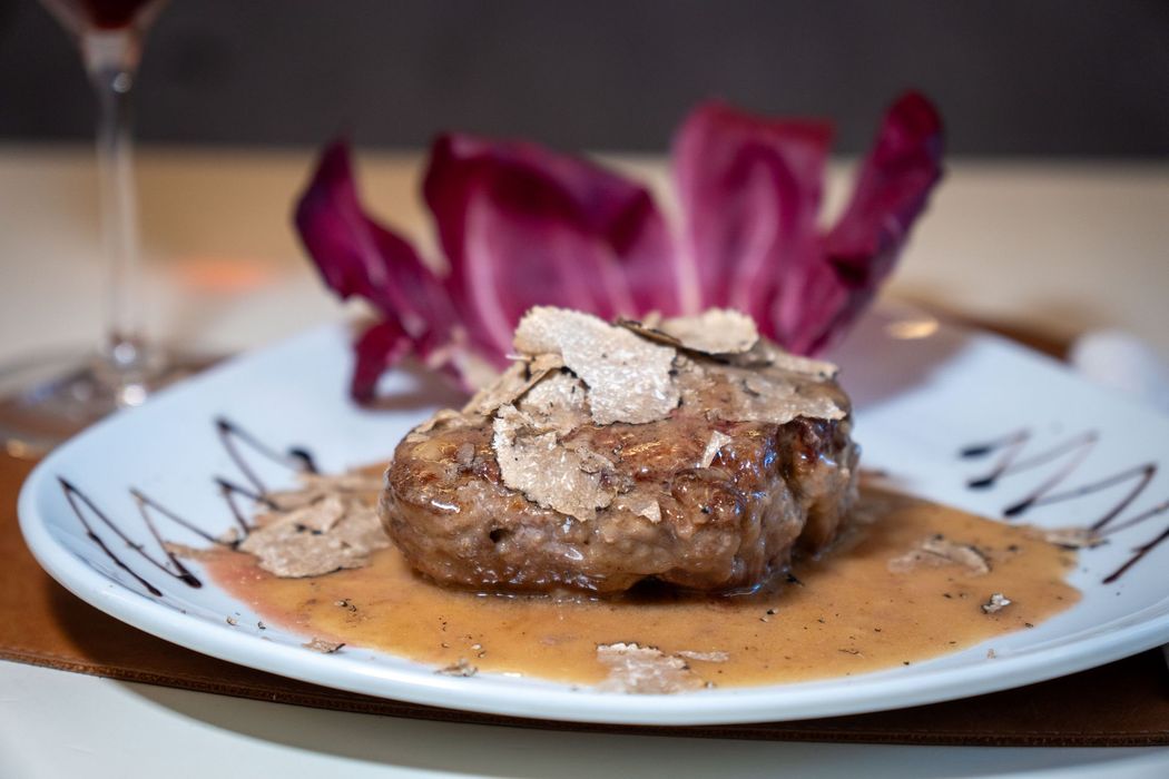 Fettine di maiale arrosto con salvia su un piatto bianco, irrorate con salsa di cottura.