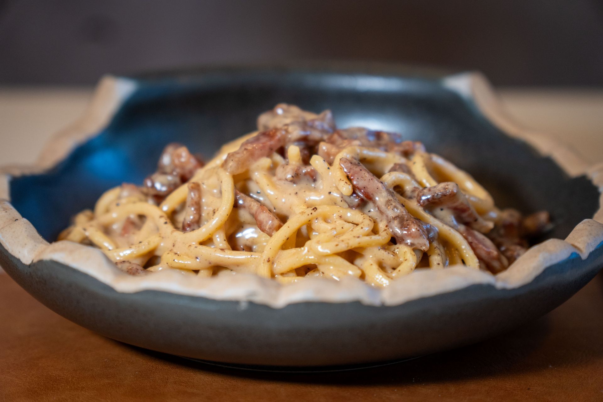Aragosta impiattata con pasta cremosa e pezzetti di pomodoro su sfondo bianco.