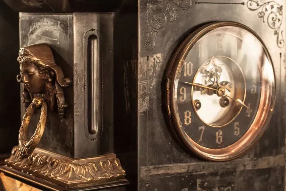 Close-up of a vintage mantel clock with ornate bronze details and a round gold face