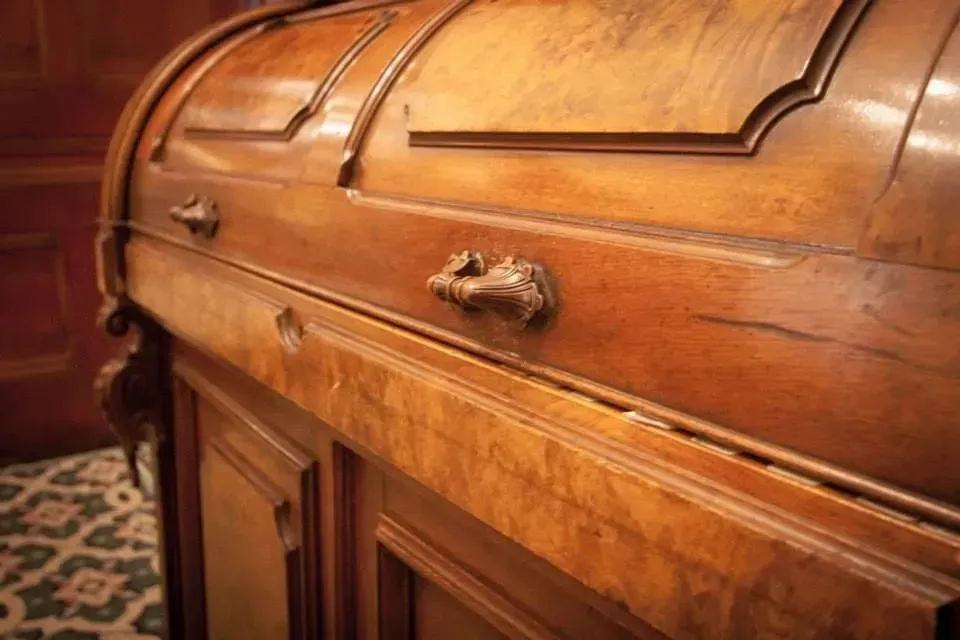 Close-up of a polished wooden casket with brass handles in a patterned room