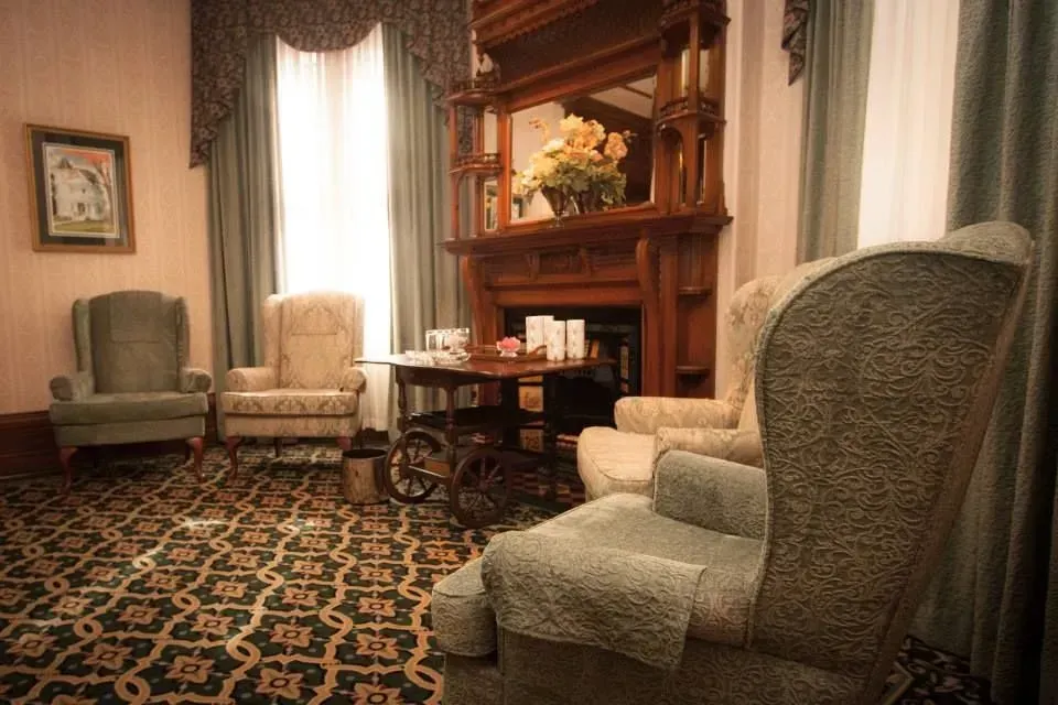 Cozy living room with upholstered chairs, fireplace, patterned rug, and soft curtains