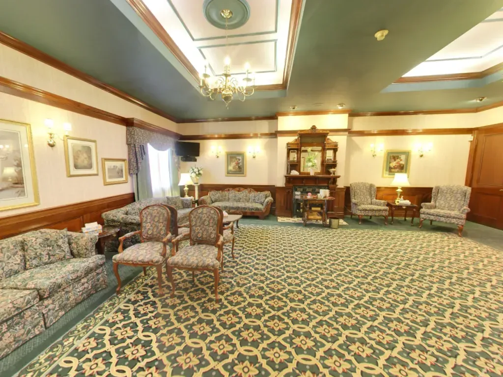Elegant hotel lobby with patterned carpet, floral sofas, wood trim, and soft ceiling lights