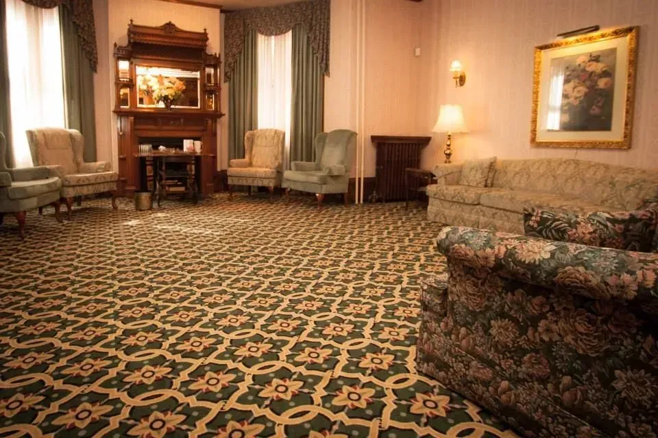Cozy hotel lobby with patterned carpet, sofas, armchairs, fireplace, and warm lighting.