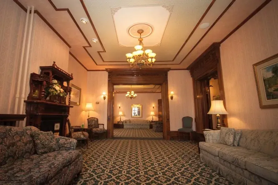Elegant hotel hallway with patterned carpet, chandeliers, sofas, and warm lighting.