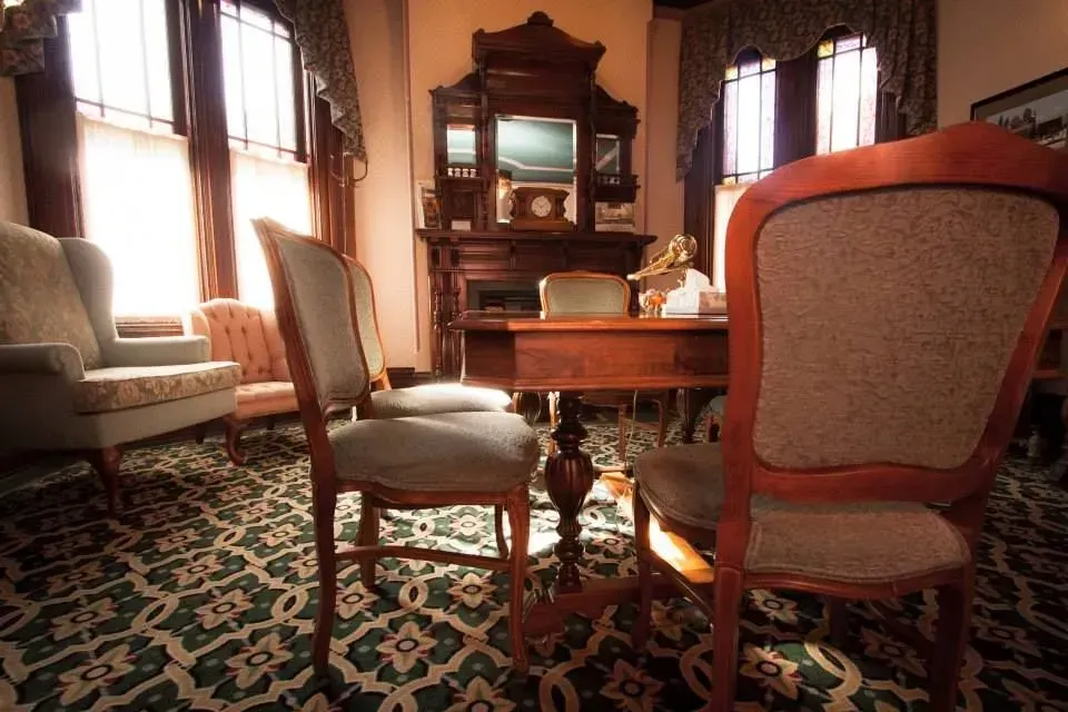 Elegant dining room with upholstered chairs, wooden table, ornate cabinet, and patterned carpet