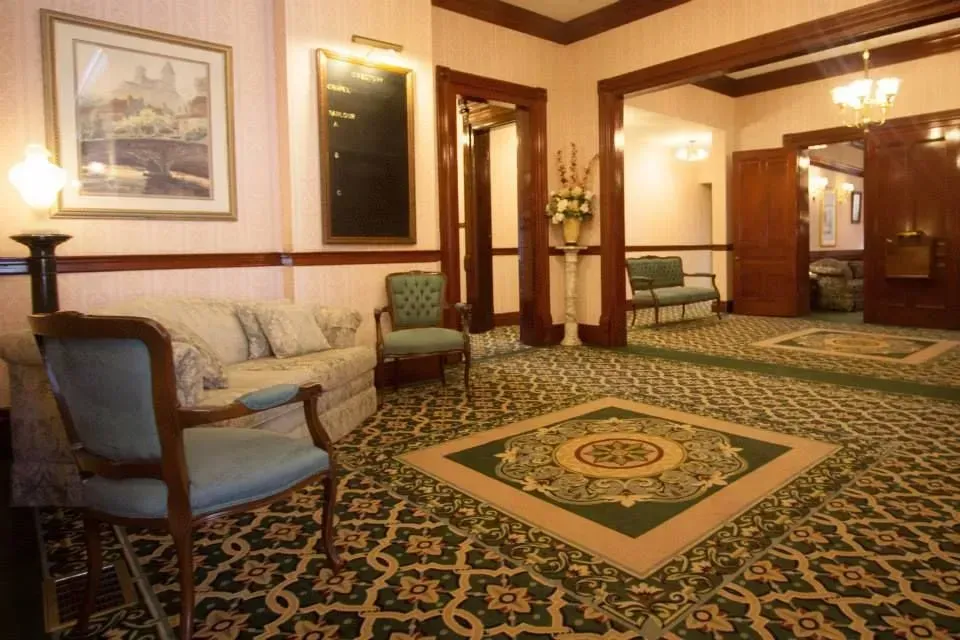 Elegant hotel lobby with patterned carpet, upholstered chairs, mirrors, and warm lighting