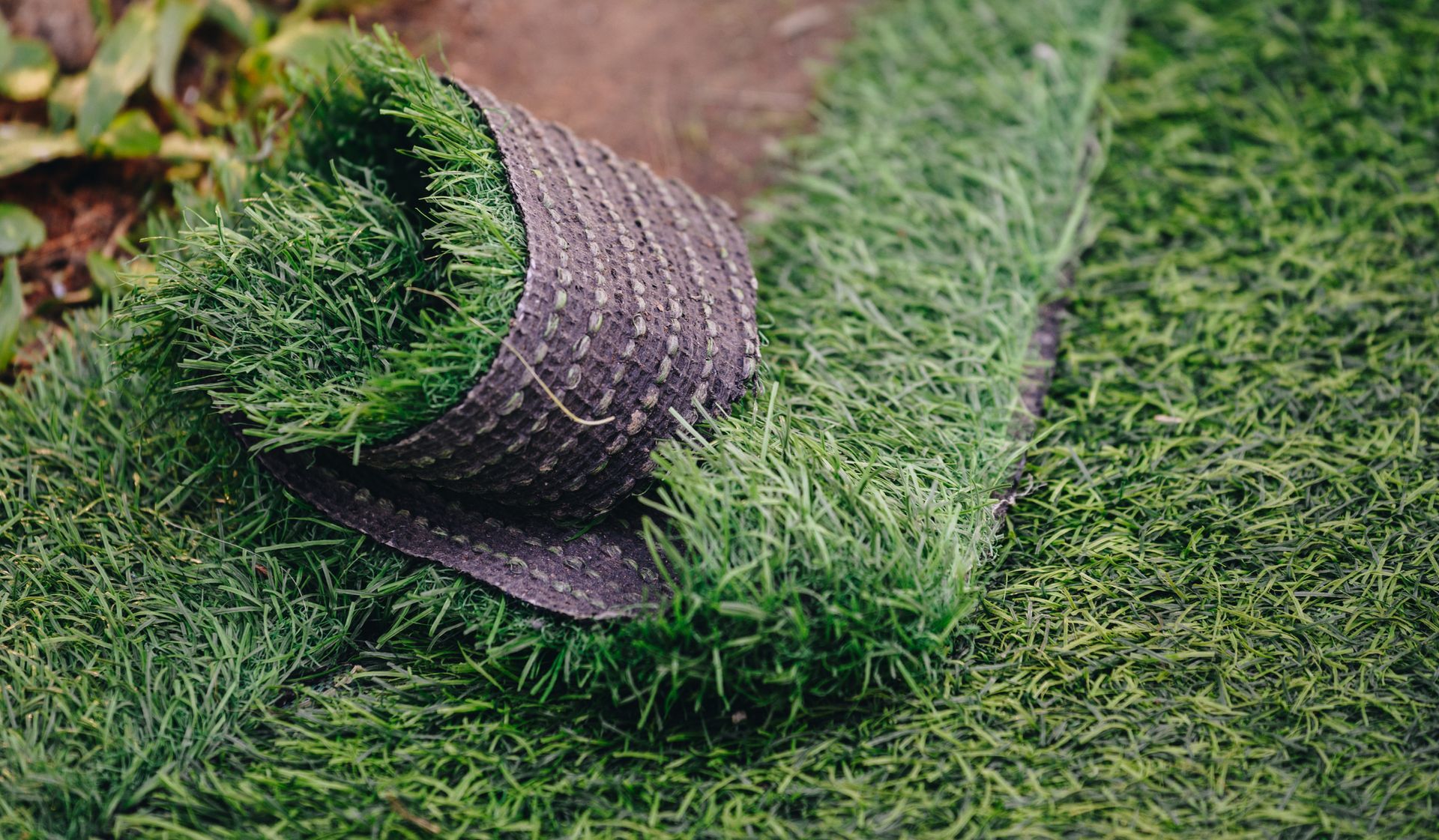 A roll of artificial grass is laying on the ground.
