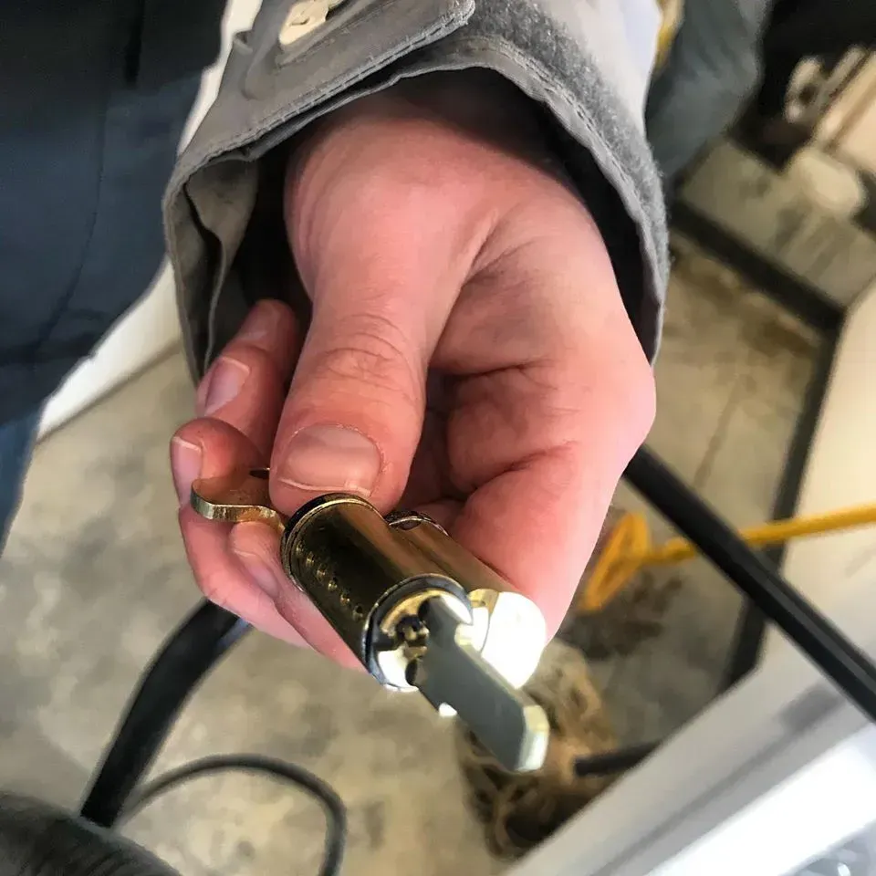 Hand holding a brass-and-black cylindrical connector with a white cable attached