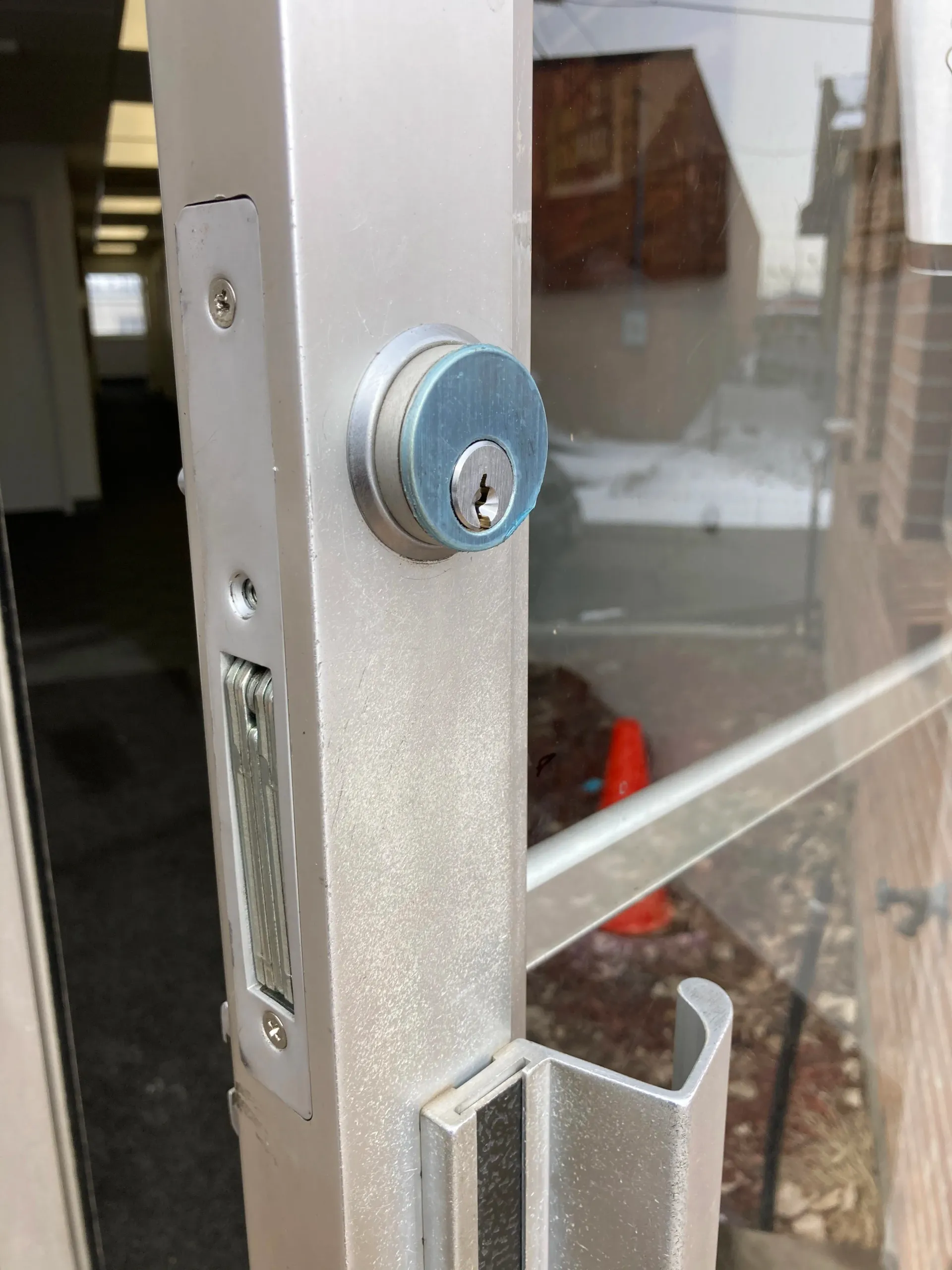 Close-up of a silver glass door with a round lock and handle.