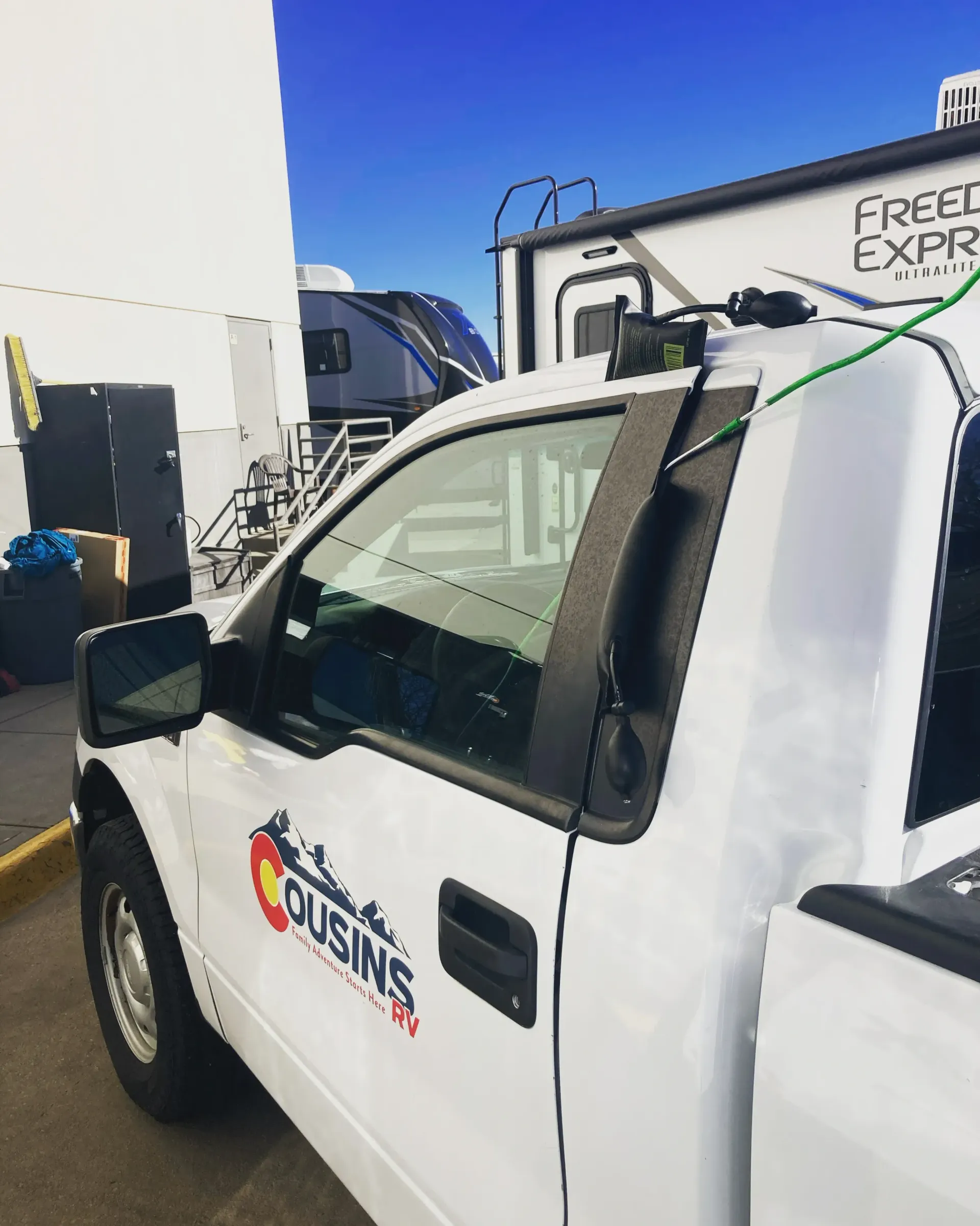White work truck with company logo parked beside a building, seen in a loading area