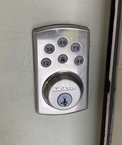 Chrome electronic keypad lock with numbered buttons on a door.