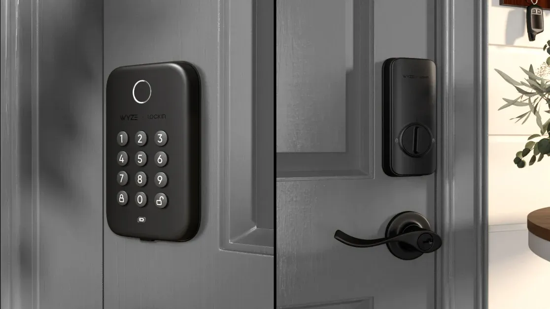Black keypad smart lock on a gray front door with a handle and deadbolt