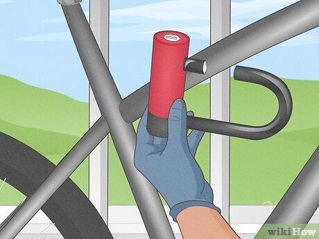 Gloved hands using a red cylinder valve with a wrench near a bicycle wheel indoors