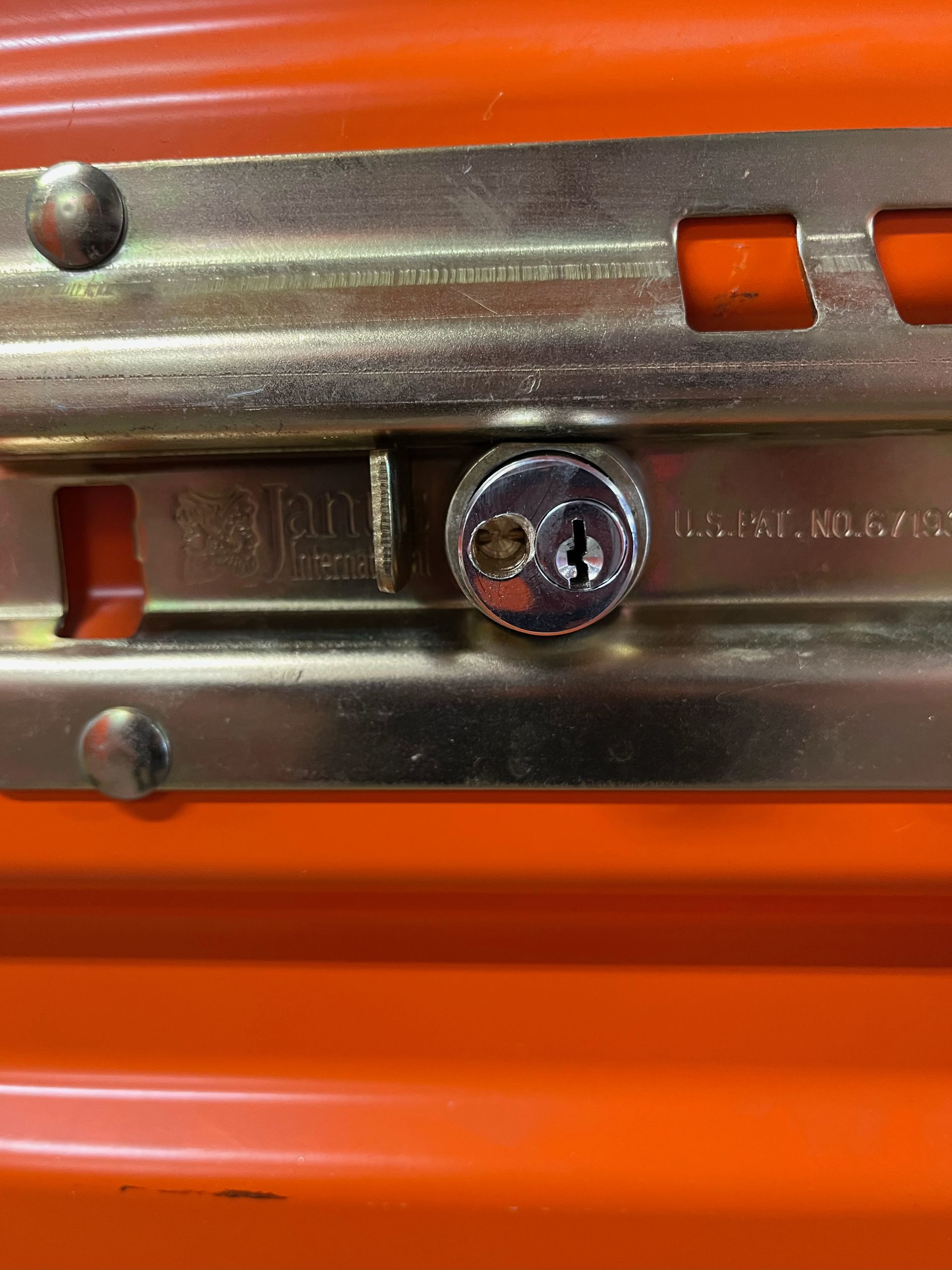 Close-up of a metal drawer slide with a screw on an orange surface.