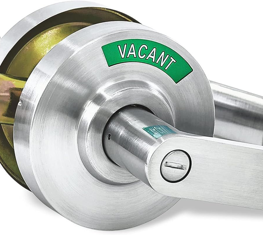 Silver door lock with a green “VACANT” sign and latch handle attached to a wooden door
