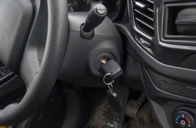 Car key in ignition beside steering wheel and dashboard controls