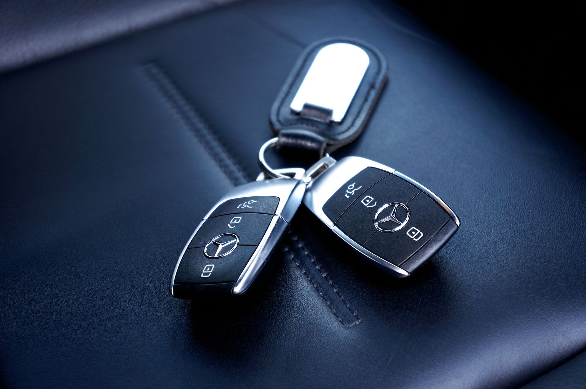 Three car key fobs on a dark leather surface