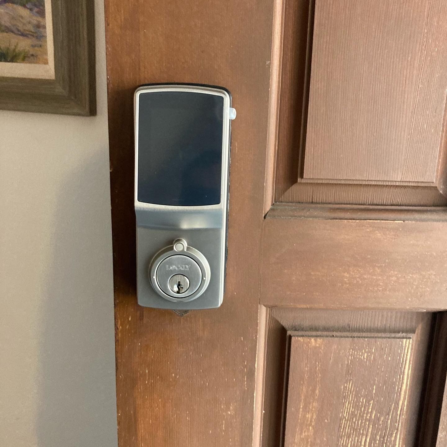 Close-up of a silver electronic deadbolt keypad on a wooden front door.