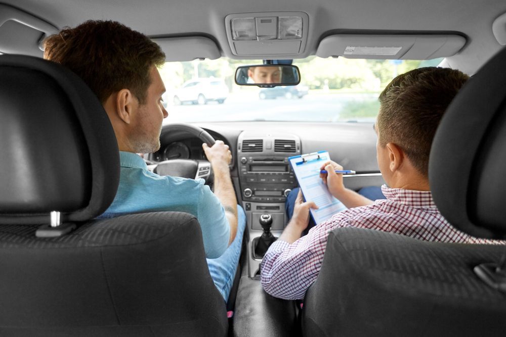 Two people in a car, one driving and one using a smartphone in the front seat.