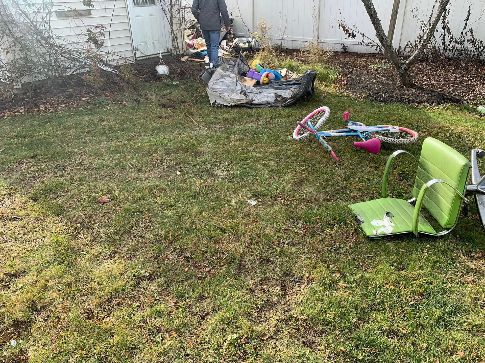 A bicycle is laying on the grass in a backyard.