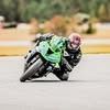 Motorcyclist in green leathers leans into a turn on a track.