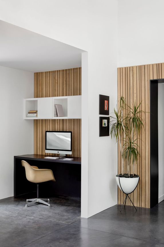 Modern minimalist home office nook with wood slat wall, desk, chair, computer, and potted plant