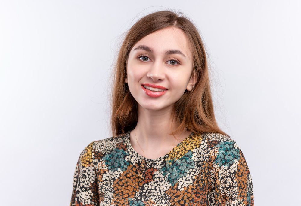 Smiling woman in a patterned blouse against a light background