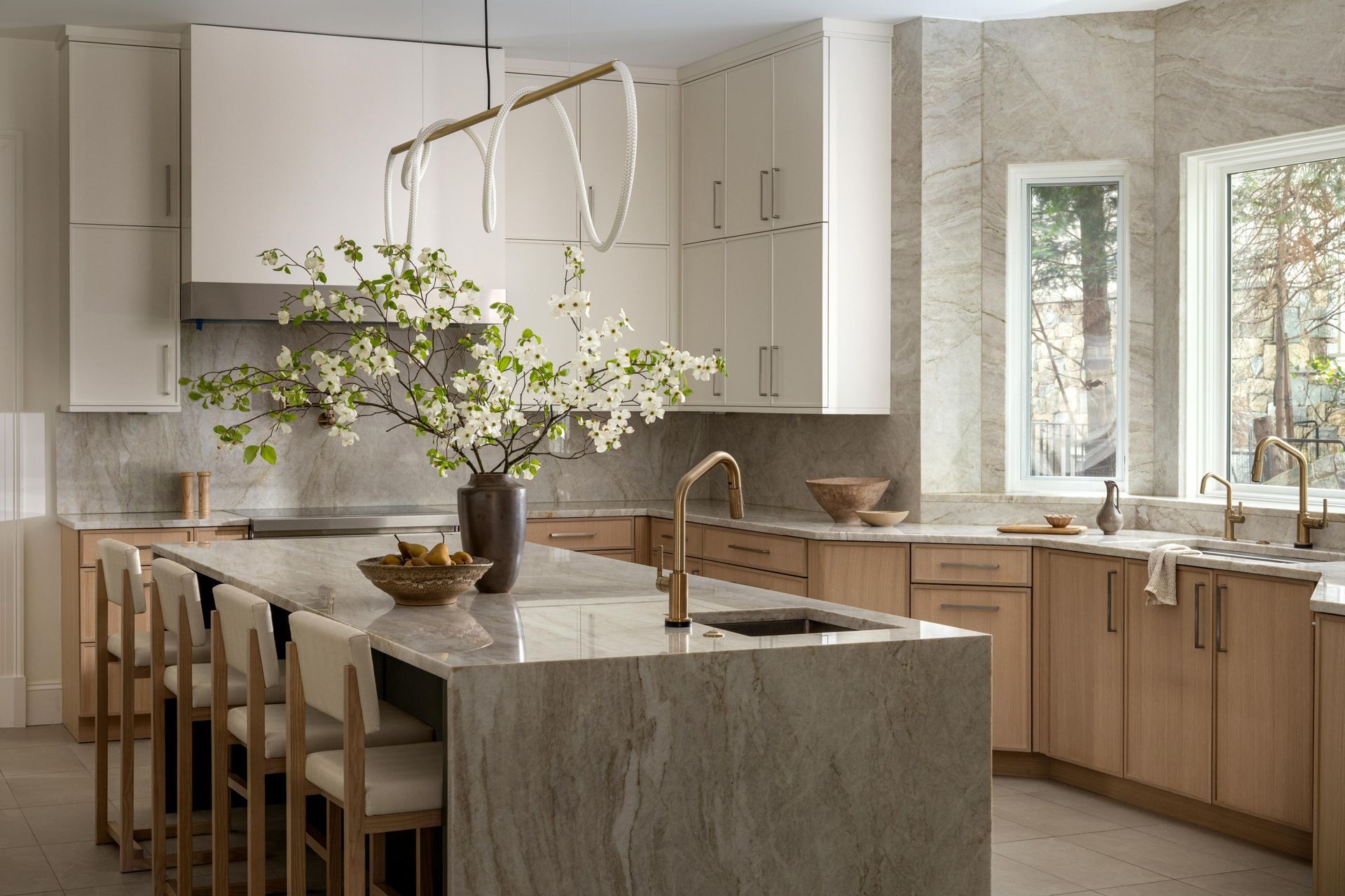 Modern kitchen with island, wood cabinetry, pendant lights, and a vase of flowering branches