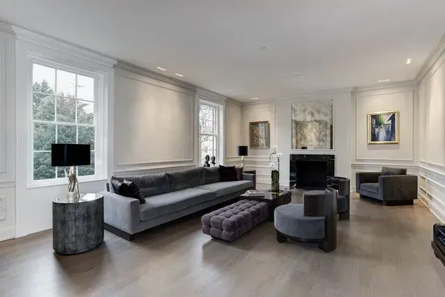 Modern living room with gray sofas, fireplace, chandelier, and large windows