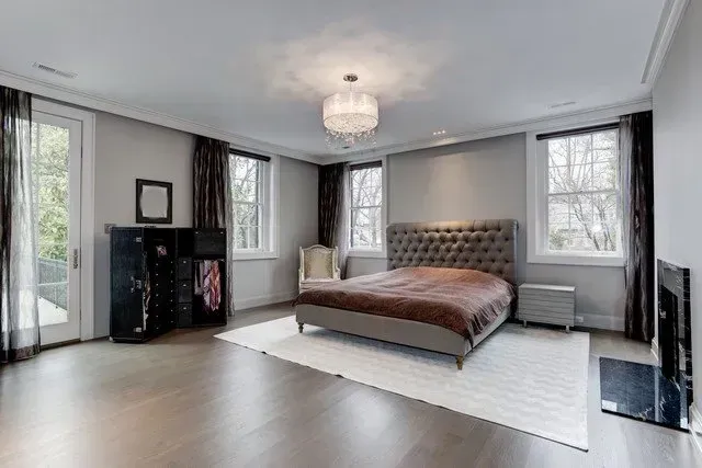 Modern bedroom with a tufted bed, large windows, dark curtains, and a white rug