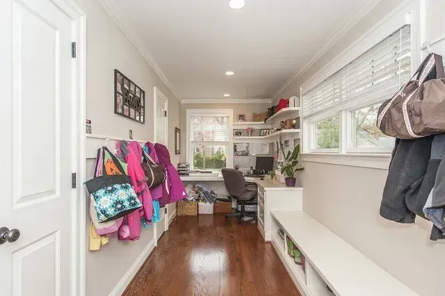 Bright hallway with children’s coats and backpacks, wood floors, and built-in white storage bench.