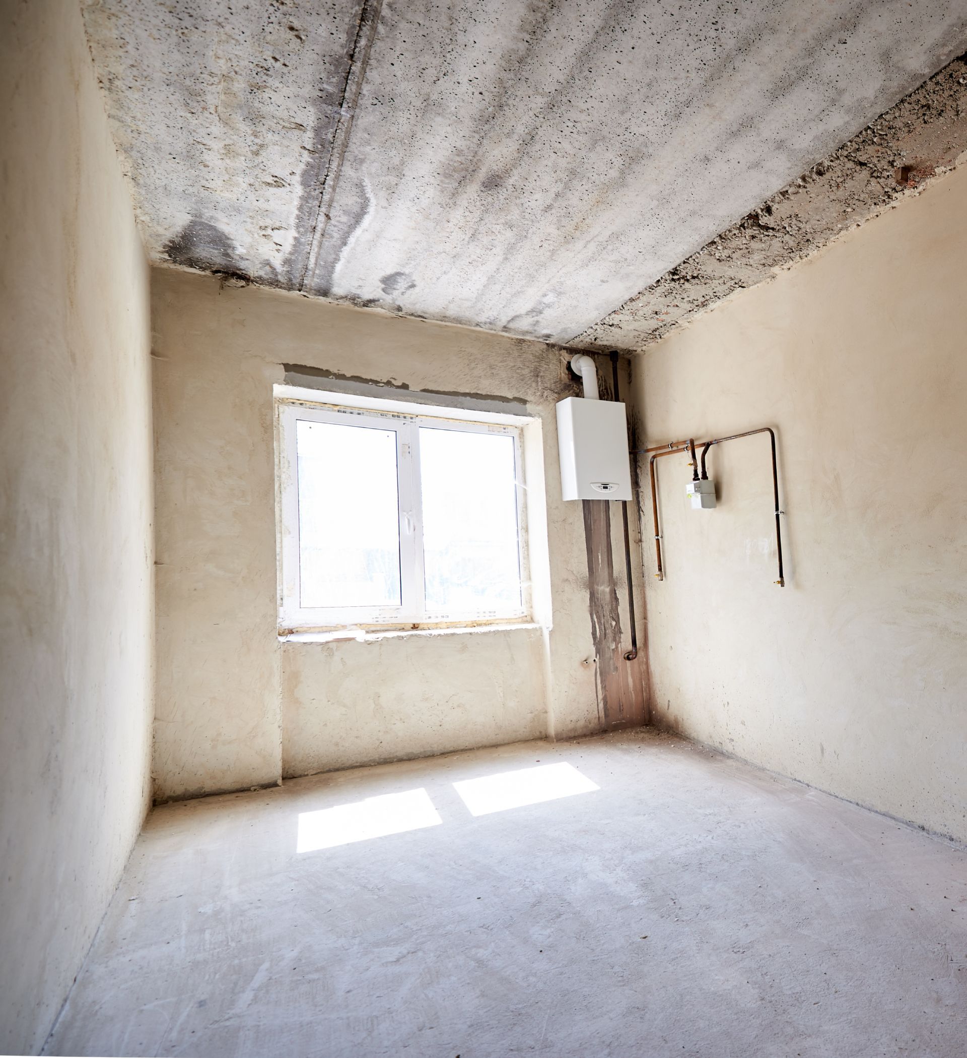 Small empty room with white walls, a window, exposed ceiling, and a utility box on the right wall