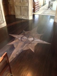 Dark hardwood floor with a large star-shaped inlay in the center of a room.