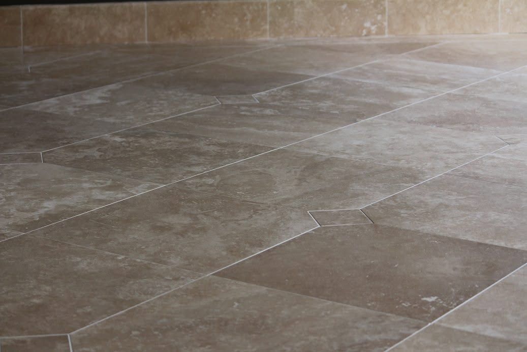 Stone-tiled floor with a light dusting of powder, viewed close up.